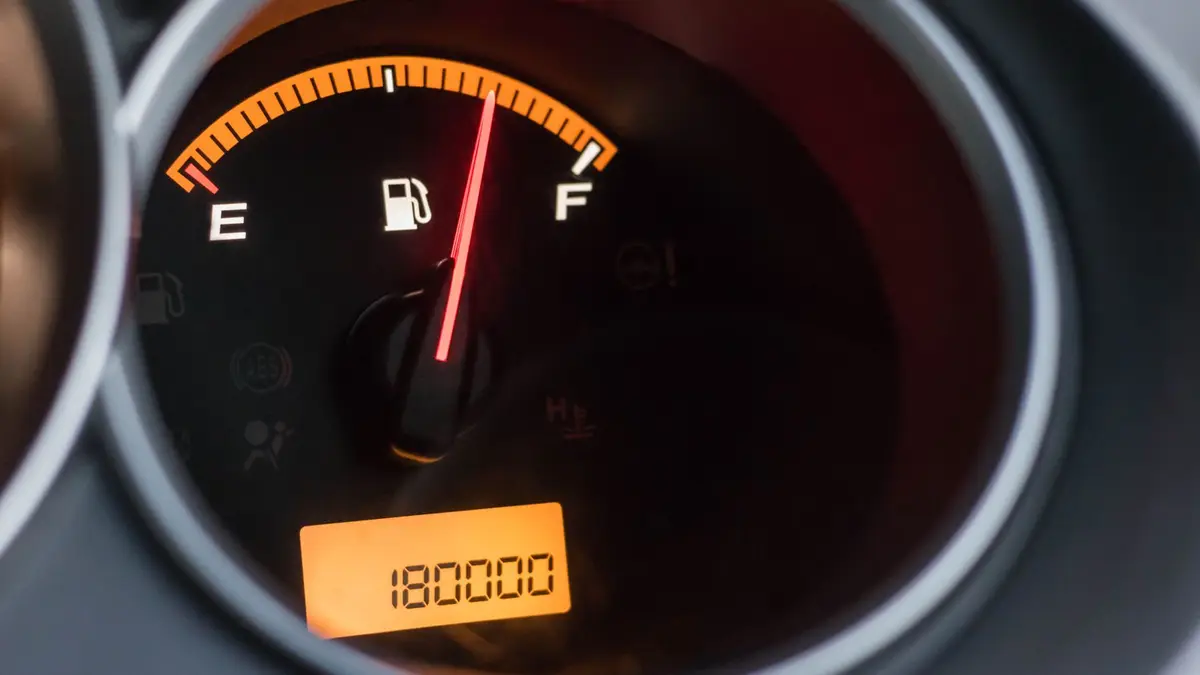 Un carnet de comptes, une calculatrice et des factures posés près d'une voiture au garage